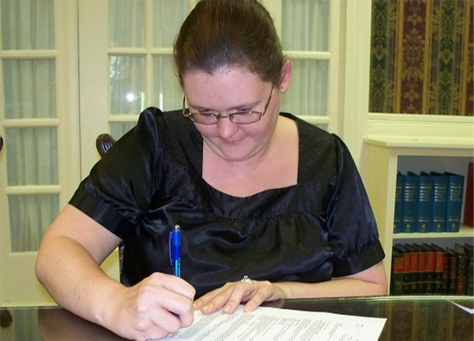 Angela B. signing the mortgage papers for her first home